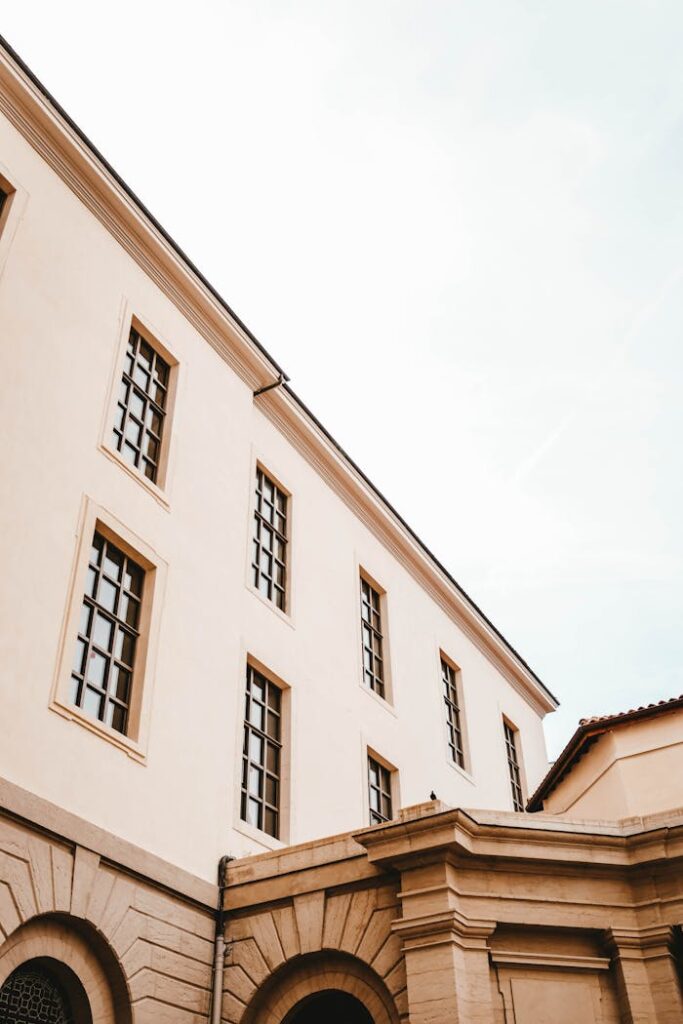 A minimalistic view of a classical building with large windows and arched design.